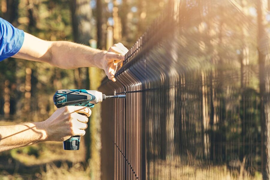 man working on his fence on his property line in San Diego, CA